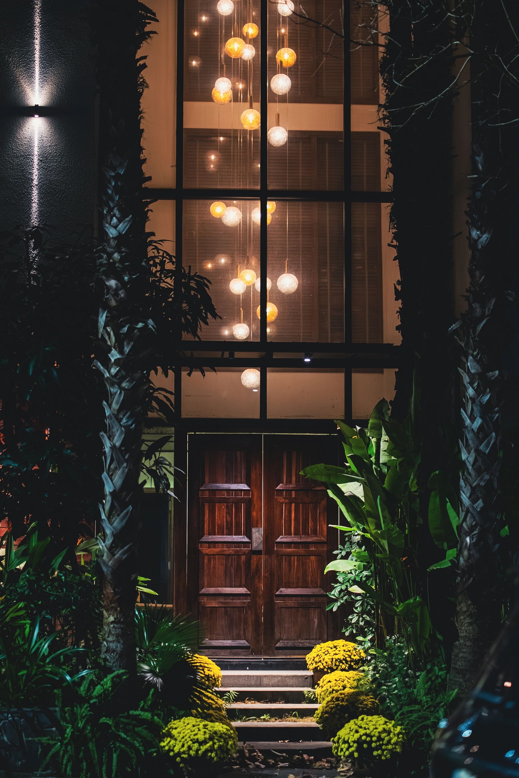 Elegant illuminated hotel entrance framed by tropical foliage at night in Alleppey